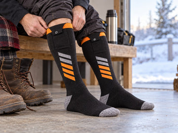 Worker wearing black and orange heated socks before putting on work boots